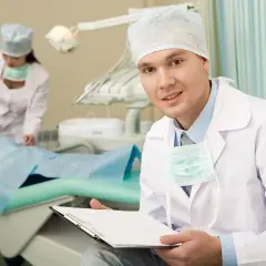 Dentysta z kartą pacjenta, obok dziewczynka na fotelu. Czy 5 to mleczak?