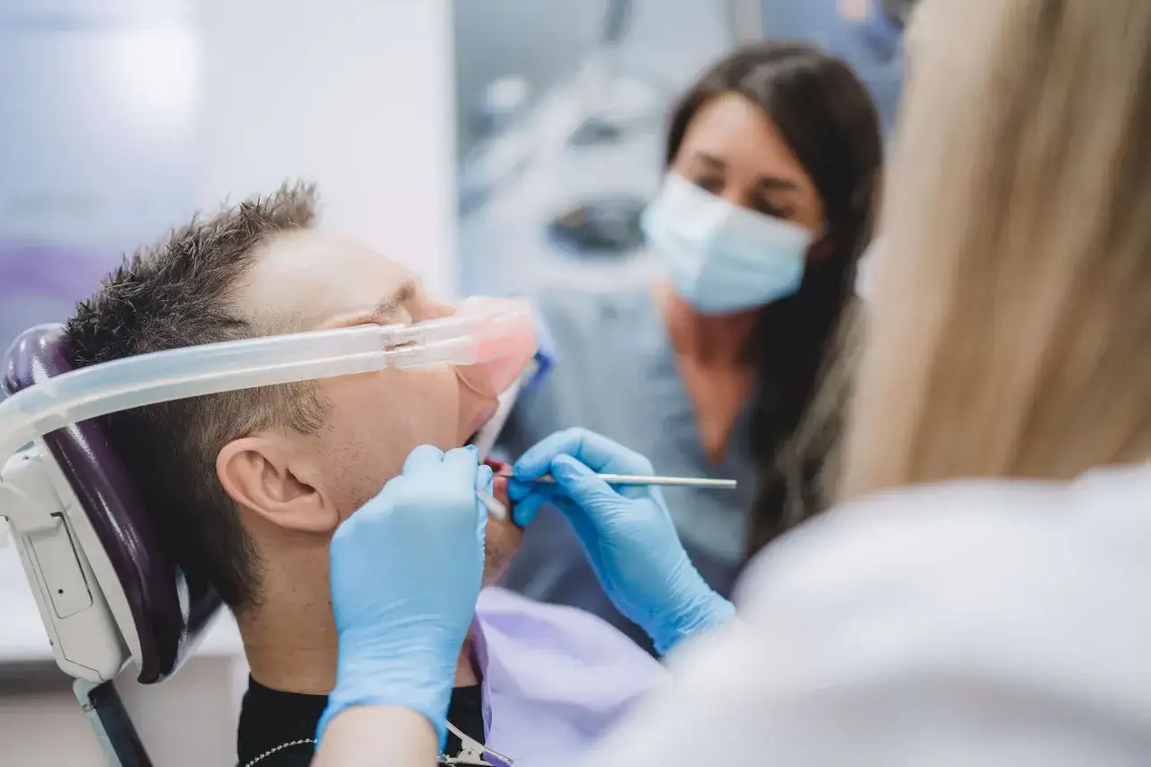 Pacjent z maską gazową na twarzy u dentysty. Zastanawiasz się, ile kosztuje wyrwanie zęba?