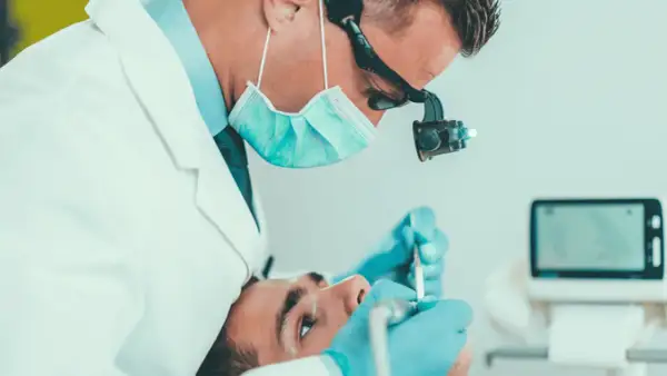 Dentysta wykonuje leczenie kanałowe jedynki, używając mikroskopu i specjalistycznych narzędzi.